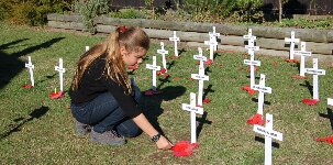 Girl placing poppy by a cross.